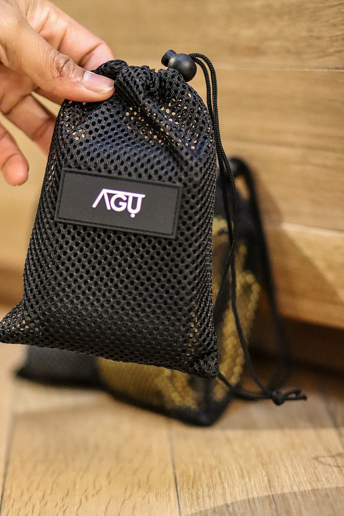 Black mesh bag containing a fitness hip band by Agu Athletics for easy transportation