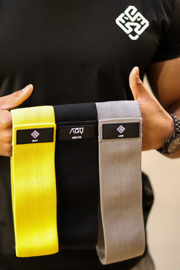 Three colours and resistance of Agu Athletics hip bands. Grey for light black for medium yellow for heavy