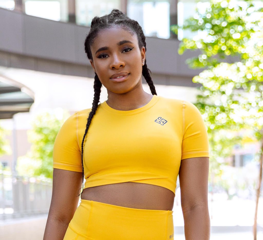 Model wearing a yellow gym crop top with lion logo