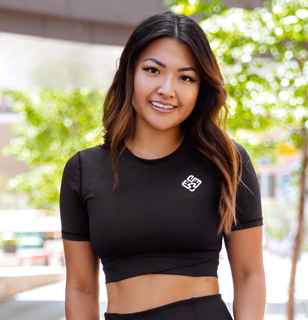 Model wearing a black gym crop top with lion logo
