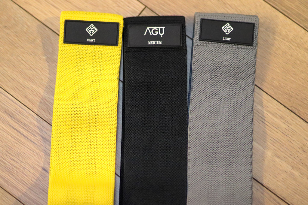 Three colours and resistance of Agu Athletics hip bands. Grey for light black for medium yellow for heavy